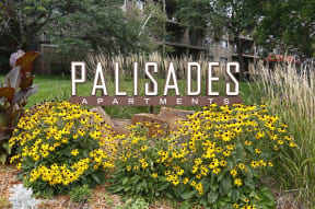 Outdoor monument sign for Palisades Apartments amongst a row of flowers.