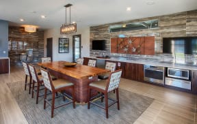 Community kitchen with eight person wood table, light wood cabinets, multiple ovens and granite countertops