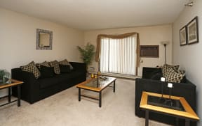 Furnished living room with two black sofas, coffee table and sliding glass door