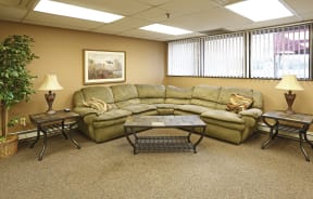 Community room with green sectional couch, stone coffee table and end tables