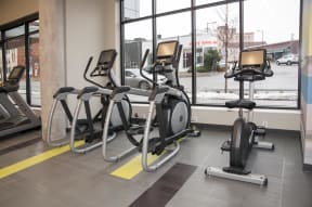 View of cardio equipment in the fitness center facing a window with view out the front of the building.