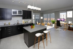 Open concept kitchen and living room with black cabinetry and pendant lighting.