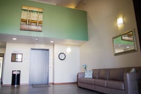 Elevator on a mint and cream colored wall with leather couch against opposite wall for lounging.