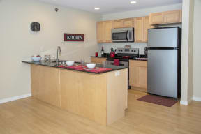 Kitchen with light wood cabinetry, large breakfast bar, and stainless steel finishes.