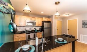 Bright and spacious kitchen with stainless steel appliances, pendant lighting above the island, and pan rack on the left side to hang pots and pans.