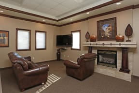 Community room with a tiled fireplace, comfortable chairs, and TV for relaxing.