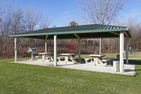 Covered community picnic area with tables and grills for outdoor dining.