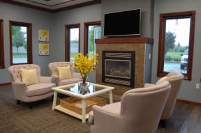 Comfortable seating, TV, and fireplace all in front of 3 gorgeous windows in the community room.