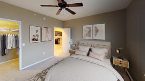 Spacious Bedroom with framed art on the walls and ceiling fan. Door in back corner opens to closet space.