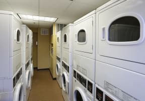 Laundry room with many washers and dryers against walls, stacked two units high