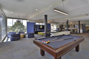 Spacious clubroom furnished with a billiards table, cozy lounging area, and dining area in the back right corner.