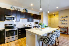 Eat in kitchen with black cabinetry, sleek stainless steel appliances, and pendant lights.