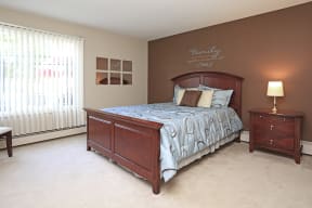 Bedroom with bed and nightstand, large windows for natural light