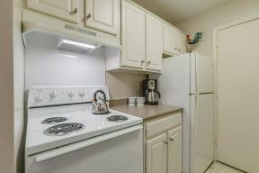 Half kitchen with white cabinets and appliances, tea pot on stove top