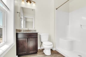 full bath with walk in shower hardwood floors walnut cabinets granite countertop ceramic toilet natural light  at Franklin Square Apartments/Townhomes, New Freedom