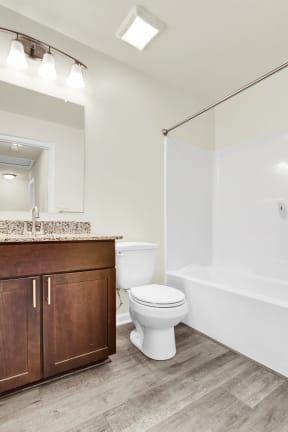 full bath with shower tub combo hardwood floors walnut cabinets granite countertop ceramic toilet