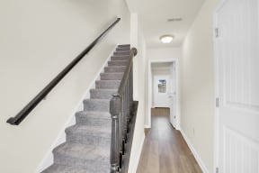 stairwell with grey carpet hardwood floors hallway leading to den