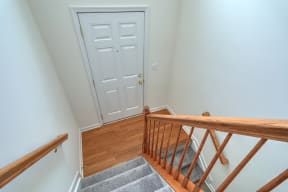 foyer with natural wood stairs and hardwood with grey carpet and white door