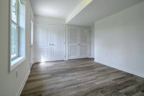 bedroom with hardwood floors and white walls with white closets