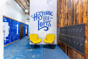 a pair of yellow chairs in front of a white brick wall with a blue writing on it