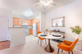 a dining area with a table and chairs and a kitchen in the background