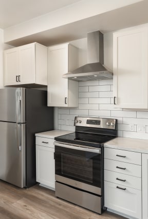 Studio kitchen with stainless steel appliances. Oven, fridge, and range hood pictured.