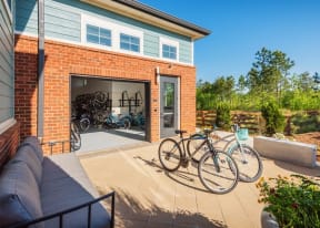 Outdoor sitting area with sofa and 2 bikes,  looking into the bicycle workshop garage