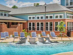 View of tiered pool entrance with two rows of lounge chairs and clubhouse in the background