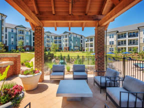 Outdoor sitting area under a pergola near flower pots and the pool by apartment buildings and lawn