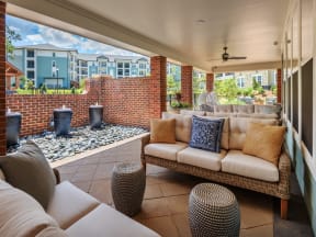 Community patio sitting area with sofas, ceiling fans, brick columns, and three small fountains