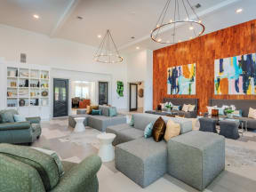 Lounge in the clubhouse with circular hanging lights, colorful wall art, sofas, and wall shelves