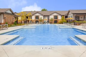 Well-maintained swimming pool and lounging chairs with parasols in One White Oak apartment rentals