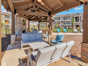 Lounge seating under a curved gazebo with a fireplace and TV in the middle and apartments behind