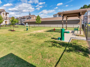 Dog park with grass, an outdoor lamp, pergola, bench, dog water fountain, and dog waste station