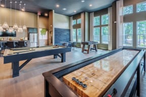 Community room with shuffleboard, billiards table, and foosball table, near kitchen and tall windows