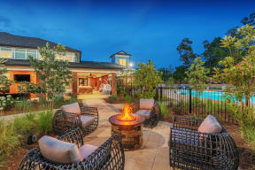 Evening view of outdoor sitting area with fire pit outside of gated pool near the clubhouse