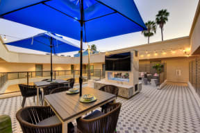 Outdoor patio with TV, Tables, Chairs and Blue Umbrella