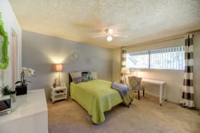 Bedroom with Large Window, Mattress with Green Comforter, Carpet, Black/White Window Curtain and Window at Pinecrest Apartments, Davis ,95616