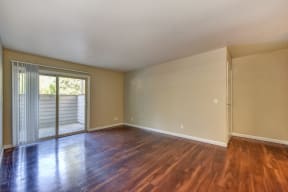 Empty Living Room with Hardwood Inspired Floor, Large Window, and White Walls