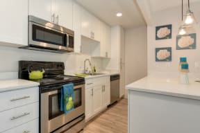 Kitchen with Hardwood Inspired Floors, , Refrigerator, White Cabinets and Small White Flower Paintings at Pinecrest Apartments, Davis