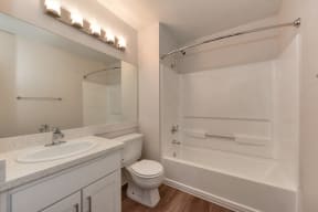 Bathroom with Wood Inspired Floor, Toilet, Vanity and Bathtub