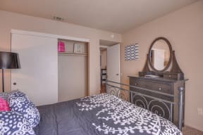 Bedroom with Closet, Dresser with Mirror, and Mattress with Gray Comforter with White Floral Design