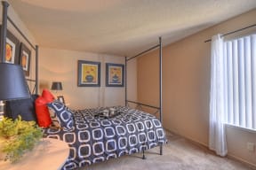 Bedroom with Large Window, Carpett, Bed with Black and White Pattern Comforter, Two Pictures of Vases on Wall