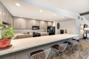 Clubhouse Kitchen with Bar Seating, White Counter, Cabinets and Refrigerator