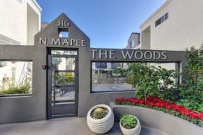 Community Entrance with "N. Maple, The Woods" Sign, Flower Bed and Cacti in Pot