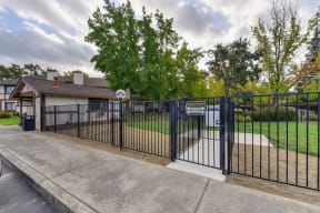 Dog Park Entrance with Sidewalk, Gate, Trees, Grass, Apartment Exterior