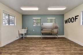 Dog Spa Tub with Hardwood Inspired Floor, Dog Washing Tub, WOOF Written in Black Letters on Wall, and Fluorescent Lights