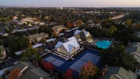 Drone Shot at Dusk with Apartment Roofs, Trees, Pool and Tennis Courtand Roads