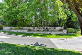 Folsom Ranch Community entrance with monument sign on a large brick wall.  Mature trees surround the wall. 