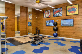 Community Fitness Center Gym with Cardio and Weight Machines, Yoga Balls and Mirrors. The walls are lined with a wooden shiplap look. 
